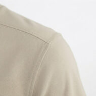 Close-up of beige fabric shoulder with visible stitching on a blazer