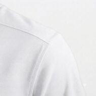 Close-up of a white shirt shoulder seam with visible stitching on a plain background.