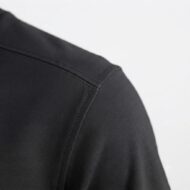Close-up of the shoulder seam on a black garment, showing neat stitching and fabric texture.