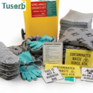 PPE and hazardous-waste setup: yellow waste bin, turquoise gloves and safety goggles, stacks of rags, and yellow 'Contaminated Waste' signs.