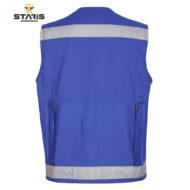 Back view of a blue work vest with a silver reflective stripe across the upper back and along the bottom hem; features two side pockets with metal rivet fasteners.