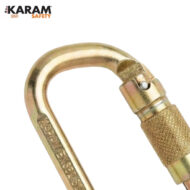 Gold carabiner with screw-lock gate, close-up; KARAM SAFETY branding visible in corner, indicating safety equipment use.