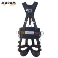 Full-body safety harness with leg loops and metal D-rings, dark blue with orange stitching, branded KARAM Safety, used for fall protection during height work.