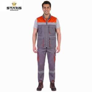 Man wearing Staris workwear: grey utility vest with orange shoulder panels and multiple pockets, matching grey pants with orange zippers and reflective leg stripes, standing against a white background with a Staris logo in the corner.