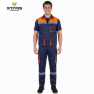 Model wearing Staris workwear: navy blue protective outfit with orange panels, multiple pockets, and gray reflective bands on the lower legs, black shoes.