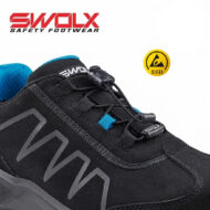 Close-up of a black SWOLX safety shoe with blue lining, quick-lace toggle, and a gray zigzag design; an ESD badge is visible in the background.