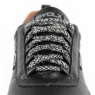 Close-up of black leather sneaker laces with a white speckled pattern threaded through the eyelets against a white background.