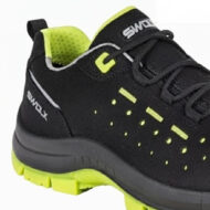 Close-up of a black athletic sneaker with neon lime accents, perforated side panels, and a chunky lime sole seen from the midfoot to heel area.