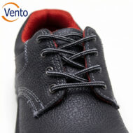 Close-up of a black textured lace-up shoe with gray laces and red interior lining; Vento logo visible in the top-left corner.