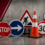Stop sign, blue right-arrow sign, construction warning sign, traffic cone, 30 sign, and striped barrier on a concrete floor indicating roadwork area